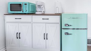 Een keuken met een wit kastje, een blauwgroene magnetron en een blauwgroene koelkast.
