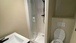 Une salle de bain avec une douche à parois de verre, un lavabo blanc et des toilettes.