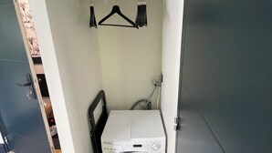 Une petite buanderie comprenant un lave-linge, un étendoir et une petite étagère.
