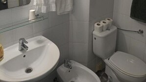A bathroom with a sink, bidet, toilet, and a mirror.