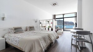 Une chambre d’hôtel moderne avec un grand lit, un bureau et une vue sur la mer.