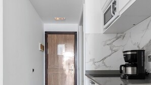 Une cuisine moderne avec une porte en bois, des armoires blanches et un pare-feu en marbre.