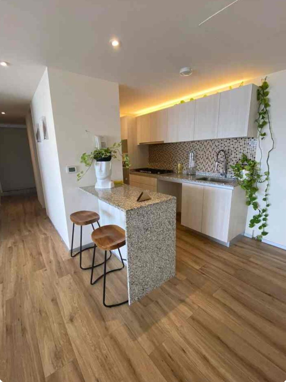 A modern kitchen with a central island, bar stools, and a backsplash with a mosaic pattern.