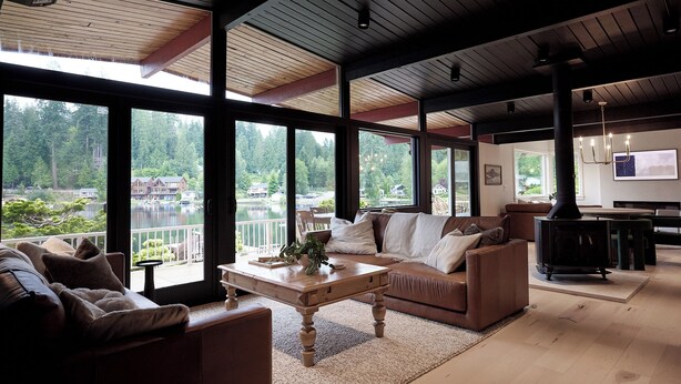 Ein geräumiges Wohnzimmer mit großem Fenster mit Seeblick, einer gemütlichen Sitzecke und einem modernen Kamin.