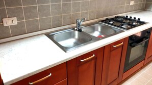 Une cuisine équipée d’un évier à deux bacs, d’une cuisinière et de meubles de rangement en bois.