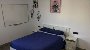 A bedroom with a white bed, blue bedding, two bedside tables, and a wall-mounted artwork. - Large renovated country house in a relaxing natural location (Pontevedra)