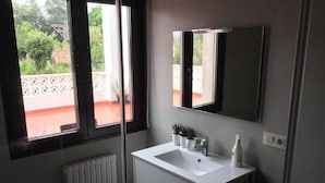 A bathroom with a white sink, a mirror above it, and a window with a view of greenery outside. - Large renovated country house in a relaxing natural location (Pontevedra)