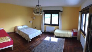 A room with two beds, a chandelier, a window with curtains, and a radiator. - Large renovated country house in a relaxing natural location (Pontevedra)