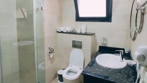 Un baño moderno con cabina de ducha de vidrio, inodoro, lavabo y espejo.