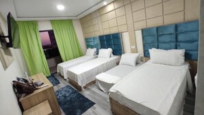 Una habitación de hotel con tres camas, un escritorio y una televisión.