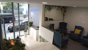 A reception area with a glass wall, a parking sign, and several blue chairs. - Hostel Central - Funchal X (Funchal)