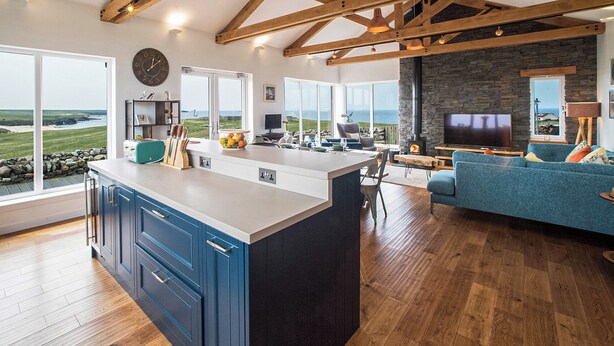 A modern kitchen with a large island, wooden beams, and a stone fireplace. - 4 bedroom accommodation in Eoropie, Isle of Lewis (Eoropie, Isle of Lewis)