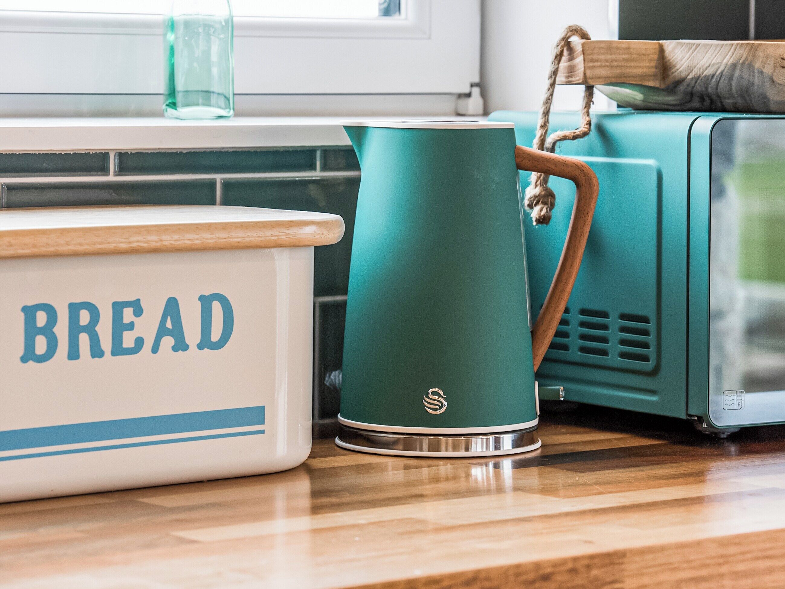 A kitchen counter with a white container labeled "BREAD" and a teal kettle.