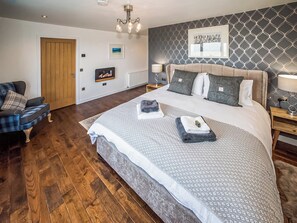 A bedroom with a large bed, a chair, a wooden door, a radiator, and a wall with a geometric pattern.