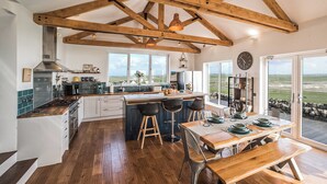 A modern kitchen with wooden beams, a dining area with a view, and a cozy seating area. - 4 bedroom accommodation in Eoropie, Isle of Lewis (Eoropie, Isle of Lewis)