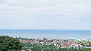 A coastal town with houses, a large blue building, and the sea in the background. - Sunny Rhyl Apartment - UK44631 (Rhyl)