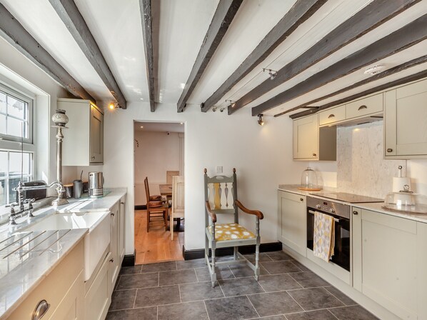 A kitchen with a marble countertop, a wooden chair, and a stove.