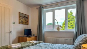 A bedroom with a bed, a television, a potted plant, and a window with curtains. - 1 bedroom accommodation in Glossop (Glossop)