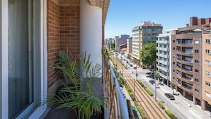 Ein Balkon mit Blick auf eine Stadtstraße, Backsteingebäude und einen klaren Himmel.