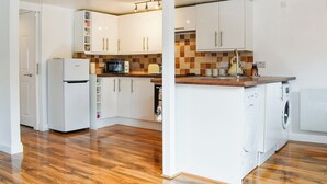 Een kleine keuken met witte kastjes, een magnetron, een broodrooster en een wasmachine.