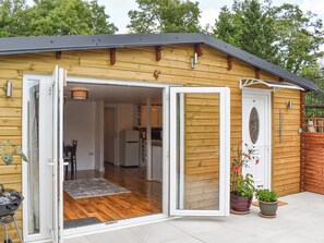 Une cabane en bois avec une porte coulissante en verre donnant sur une cuisine et un coin repas.