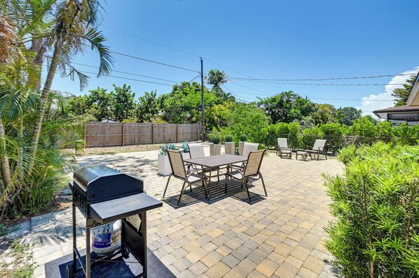 Une terrasse extérieure avec un barbecue, une table et des chaises.