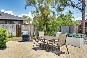Une terrasse avec un barbecue, une table et des chaises.