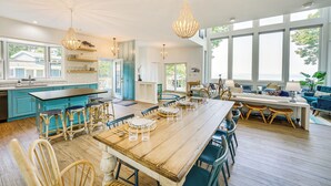 A spacious kitchen with a large island, bar stools, and a dining area with a long table and chairs. - Private Beachfront Lake Michigan Rental w/ Kayaks (Pentwater)