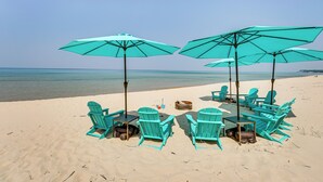 A beach setting with turquoise chairs and umbrellas arranged for outdoor dining. - Private Beachfront Lake Michigan Rental w/ Kayaks (Pentwater)