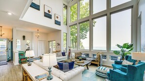 A spacious living area with a high ceiling, large windows, and a view of the outdoors. - Private Beachfront Lake Michigan Rental w/ Kayaks (Pentwater)