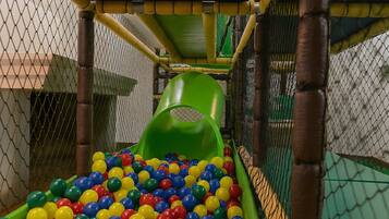 A play area with a slide and a ball pit filled with multicolored balls.