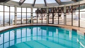 Une vaste piscine intérieure aux parois en verre transparent, offrant une vue imprenable sur le paysage environnant.