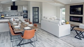 A spacious living area with a dining table, sofas, and a kitchen in the background. - River Tees Lodge - UKC4064 (Great Ayton, near Stokesley)