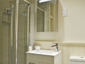 A bathroom with a glass-enclosed shower, a white sink, and a mirror above the sink.