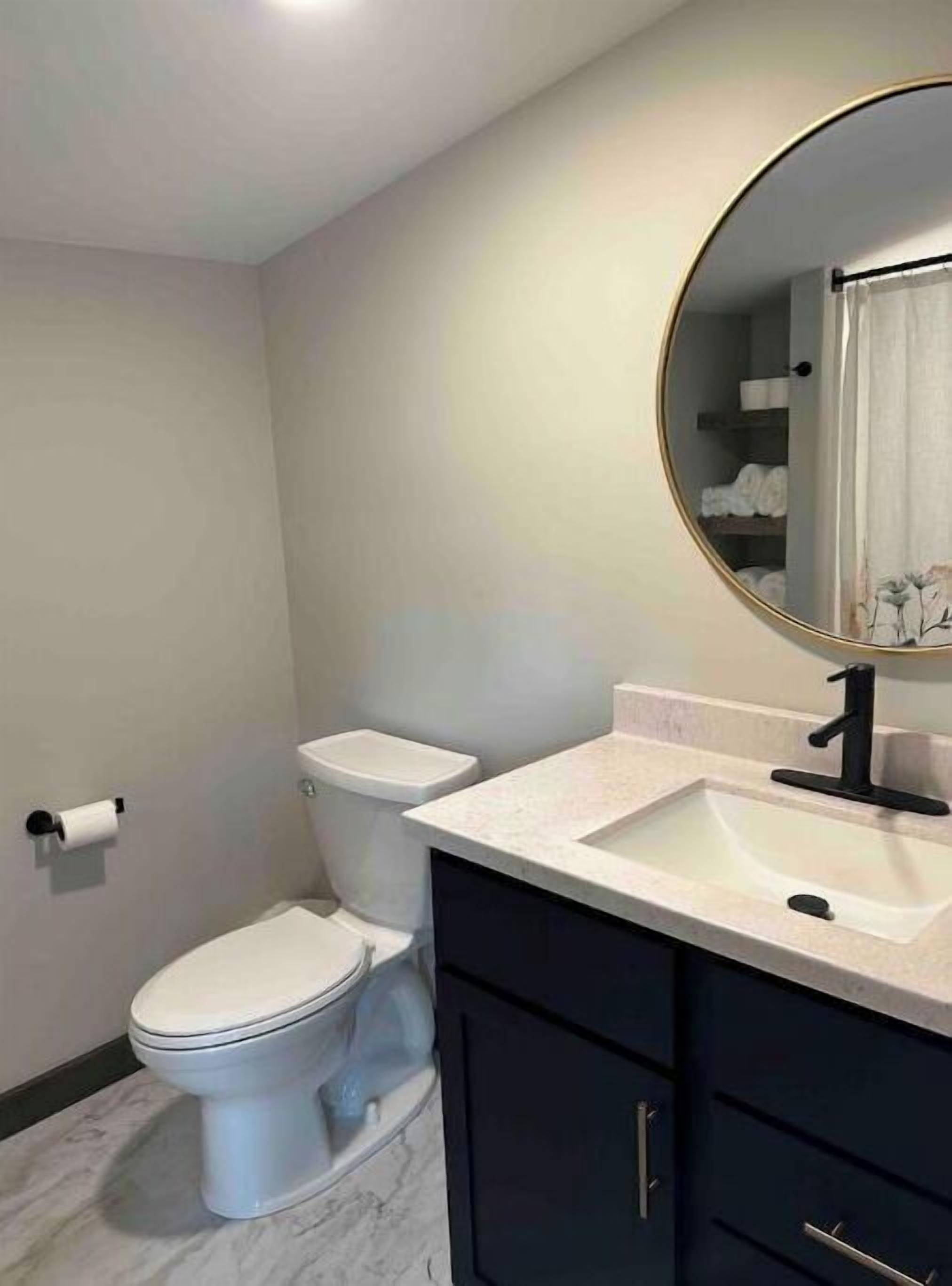 Un baño con inodoro, lavabo y espejo.