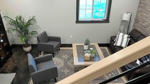 Un salon avec un canapé, des fauteuils, une table basse et une fenêtre.