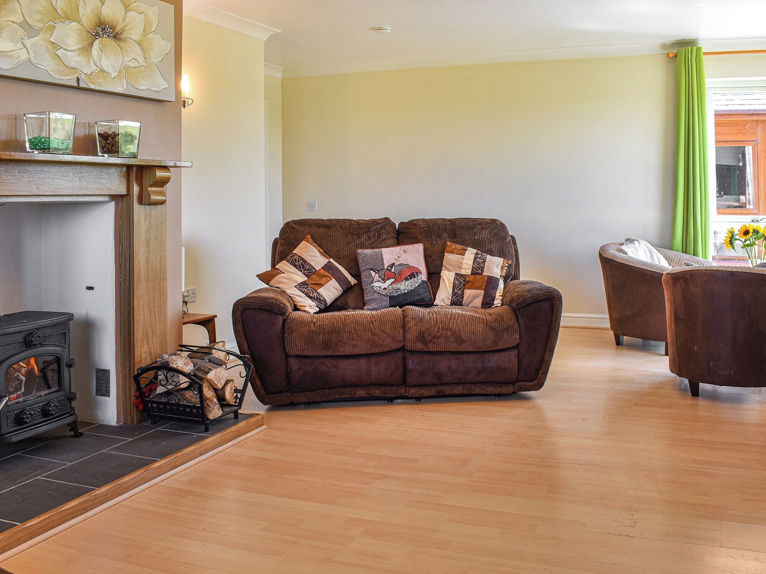Ein gemütliches Wohnzimmer mit einem braunen Sofa, einem Kamin und einem grünen Vorhang.