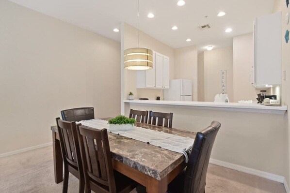 A dining area with a marble table, wooden chairs, a hanging light fixture, and white cabinets in the background. - Third floor unit in Bahama Bay (Davenport)