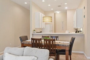 Uma sala de jantar com mesa, cadeiras e bancada de cozinha com armários.