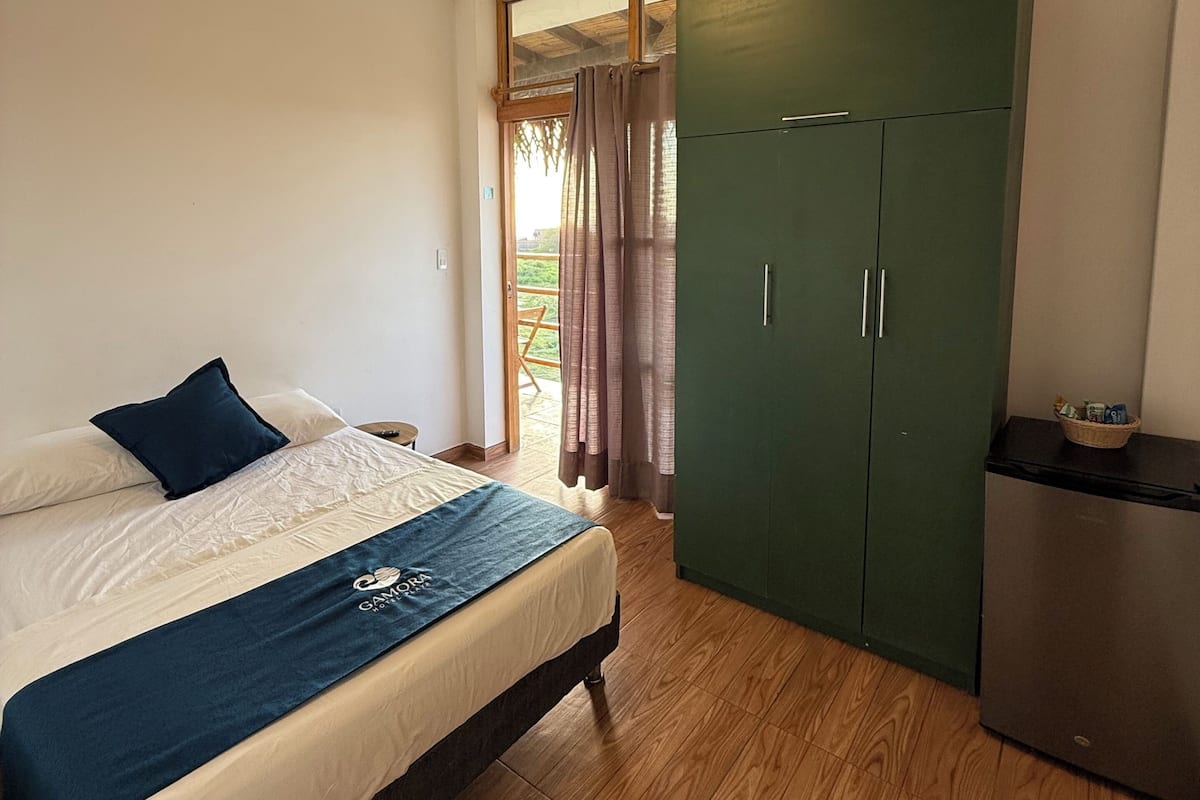 Una camera da letto con un letto, una ventola a soffitto, un armadio e un frigorifero.