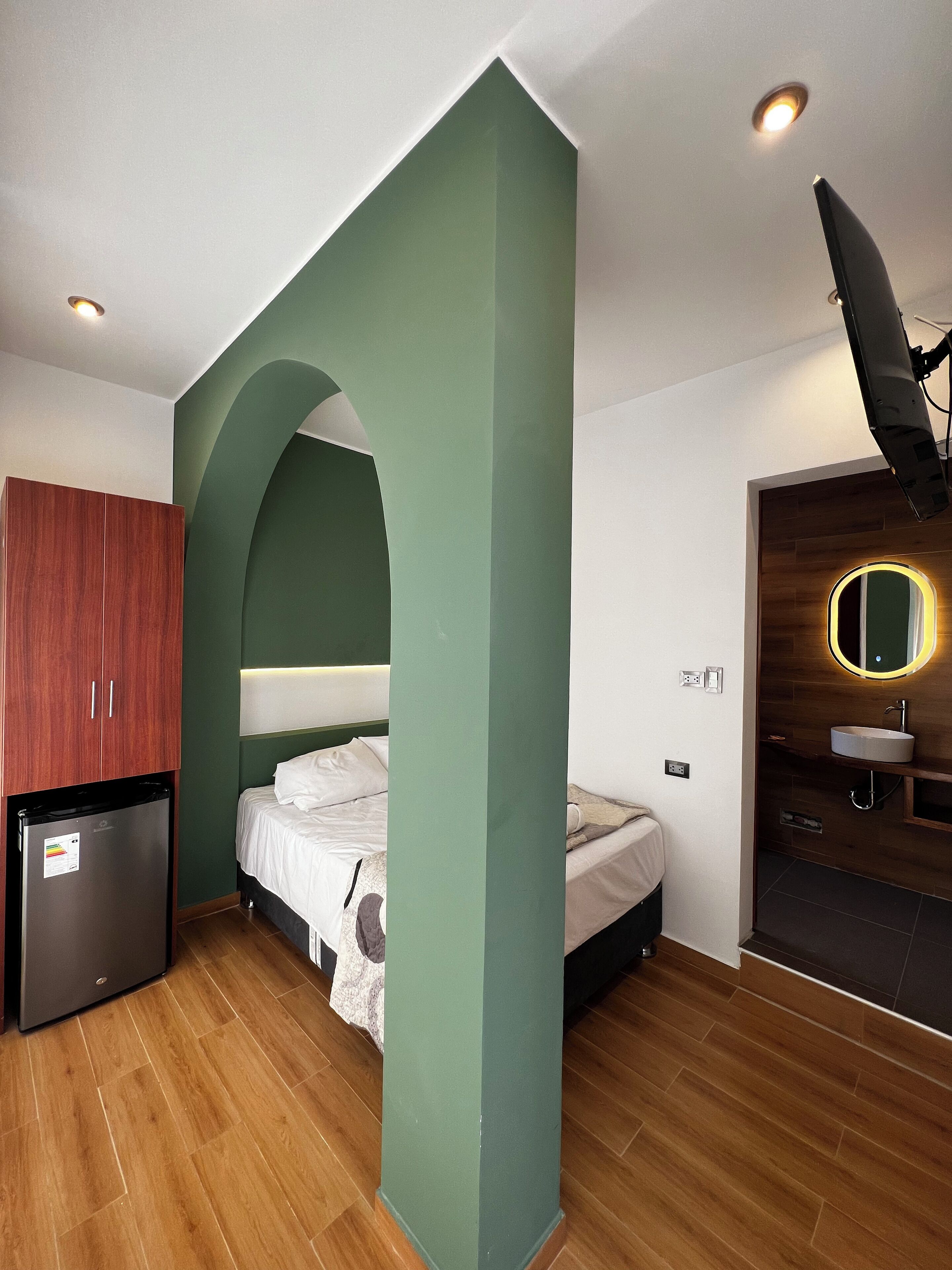 Una habitación pequeña con cama, kitchenette y baño.