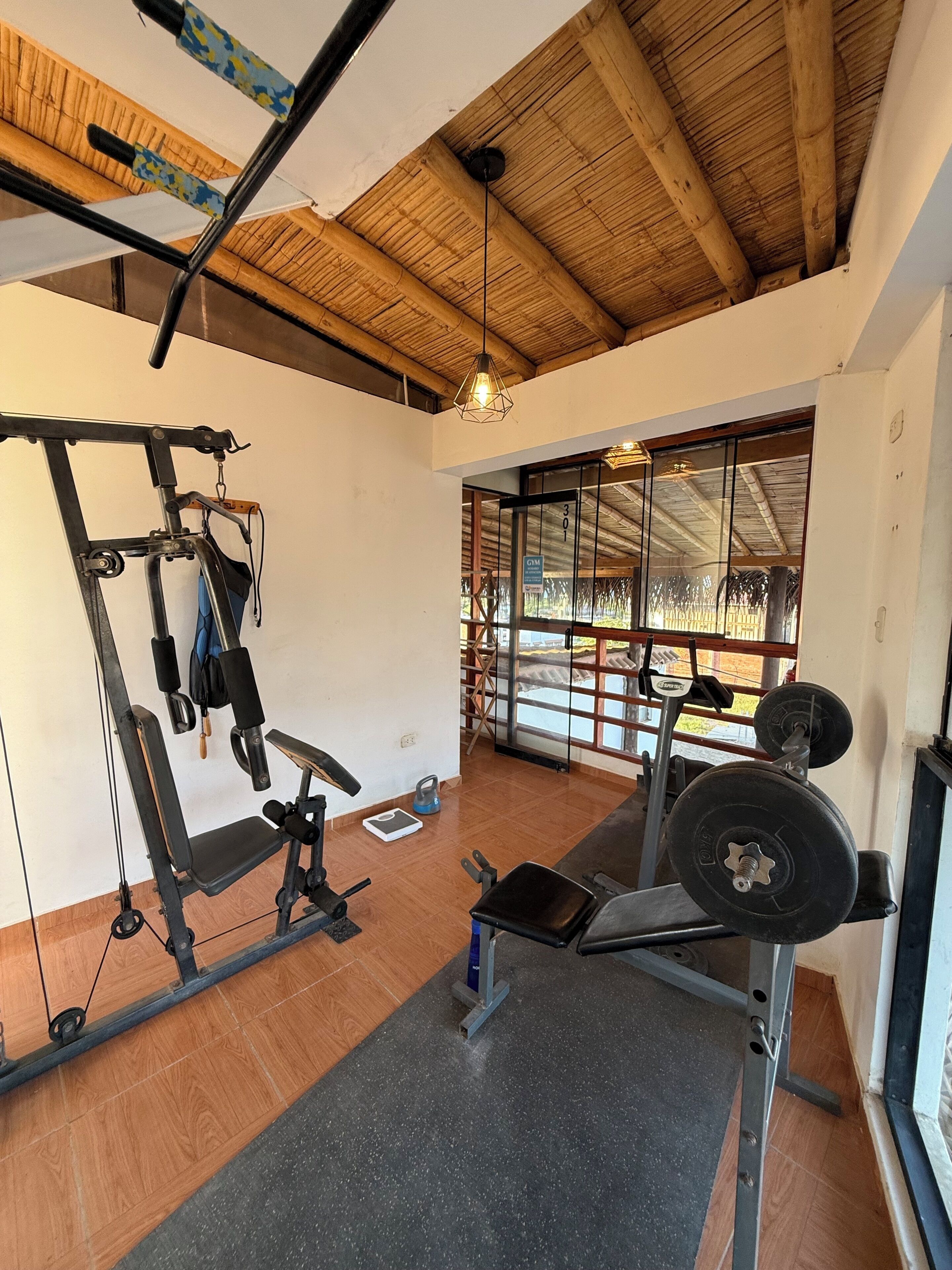 A gym with exercise equipment, a weight bench, and a large window with a view.