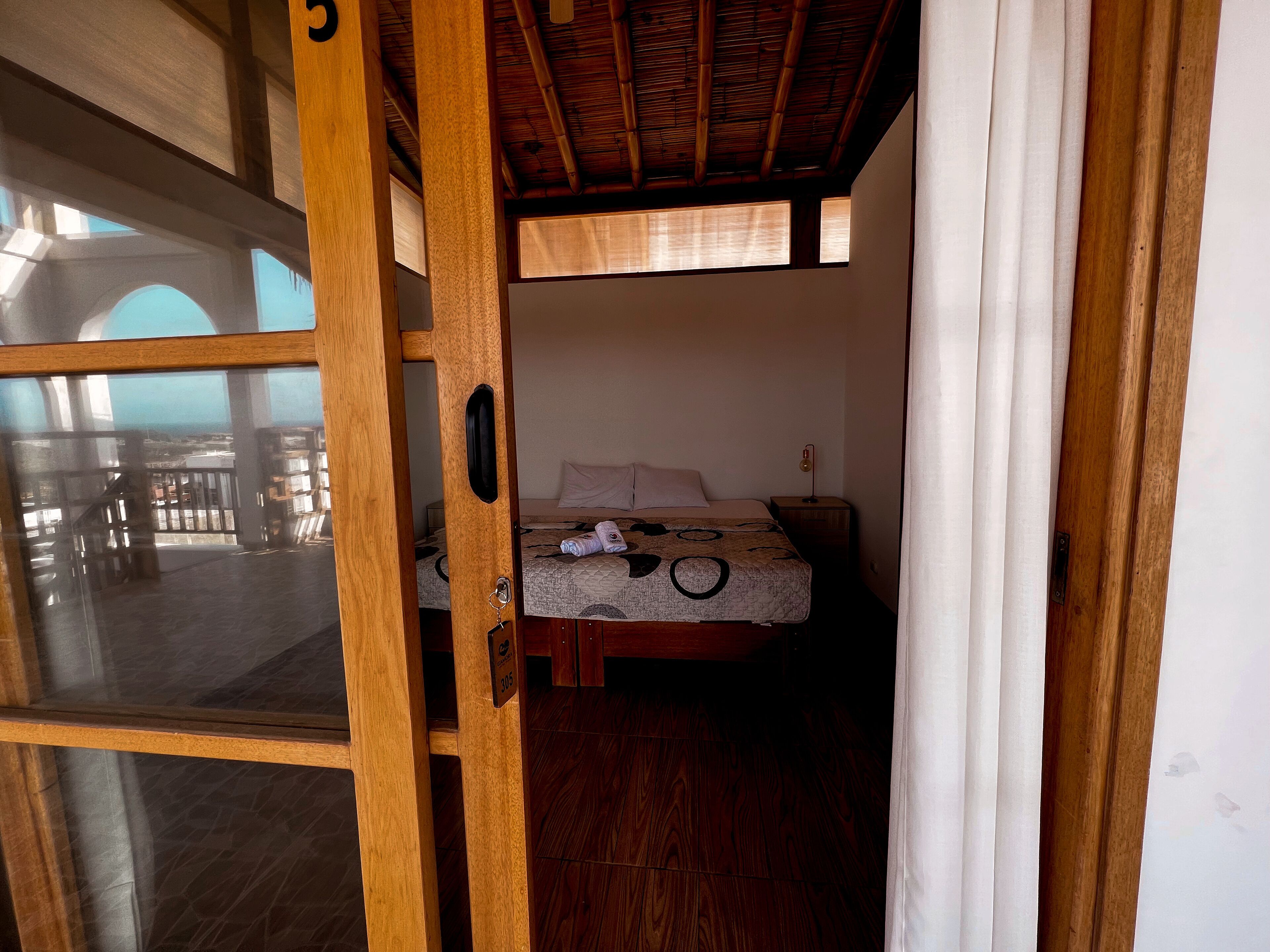 A room with a bed, wooden flooring, and a window.