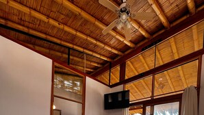 A room with a bed, a ceiling fan, a TV mounted on the wall, and large windows. - Gamora Hotel Playa (Los Organos)