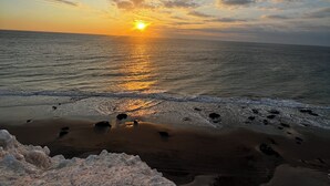 A beach with a sunset, waves, and a rocky foreground. - Gamora Hotel Playa (Los Organos)