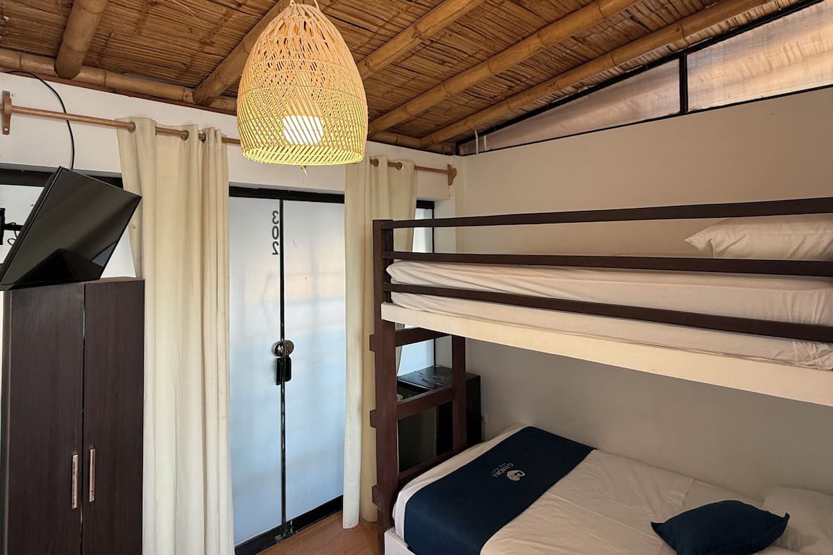 Una stanza con un letto a castello, una scrivania con un computer, un armadio e una lampada a sospensione.
