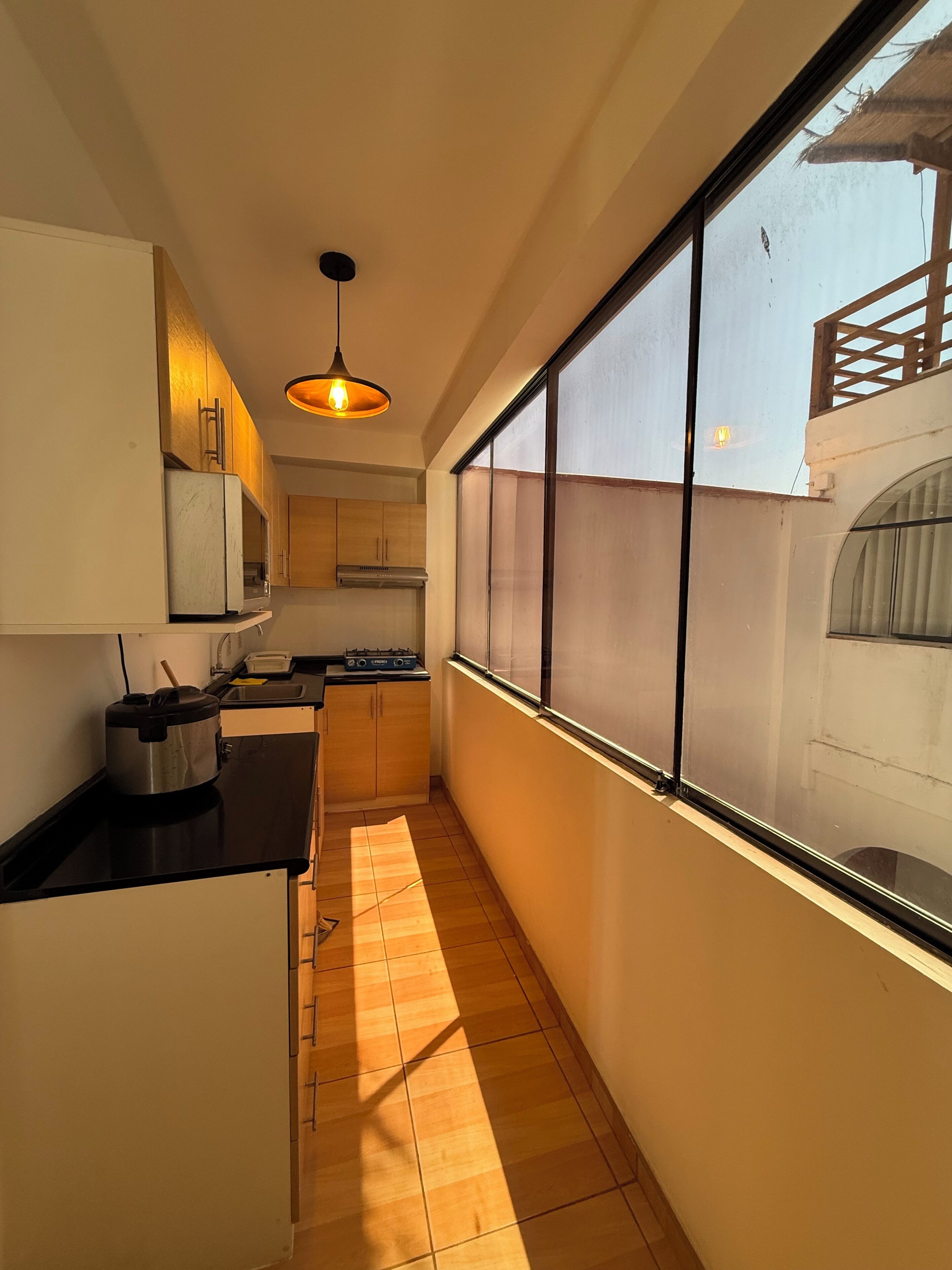 Una cocina estrecha con estufa, lavamanos y ventana.