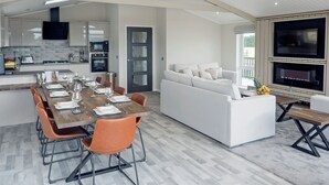 A spacious living area with a dining table, sofas, and a kitchen in the background. - Stan Hollis Lodge - UKC4063 (Great Ayton, near Stokesley)