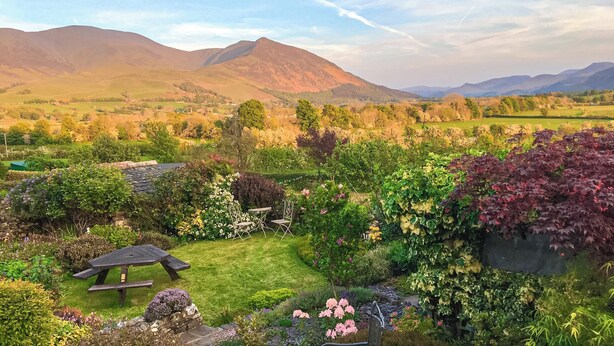 A garden with a picnic table and chairs, surrounded by lush greenery and flowering plants. - 2 bedroom accommodation in Bassenthwaite, near Keswick (Bassenthwaite, near Keswick)