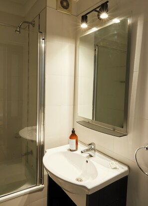 A bathroom with a glass shower enclosure, a white sink, and a mirror above the sink. - Hestia at Paraguay 4700 (Buenos Aires)